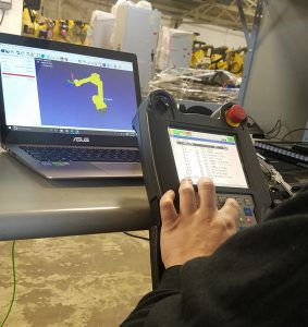 We Test Image image of technician using a teach pendant and testing a robot